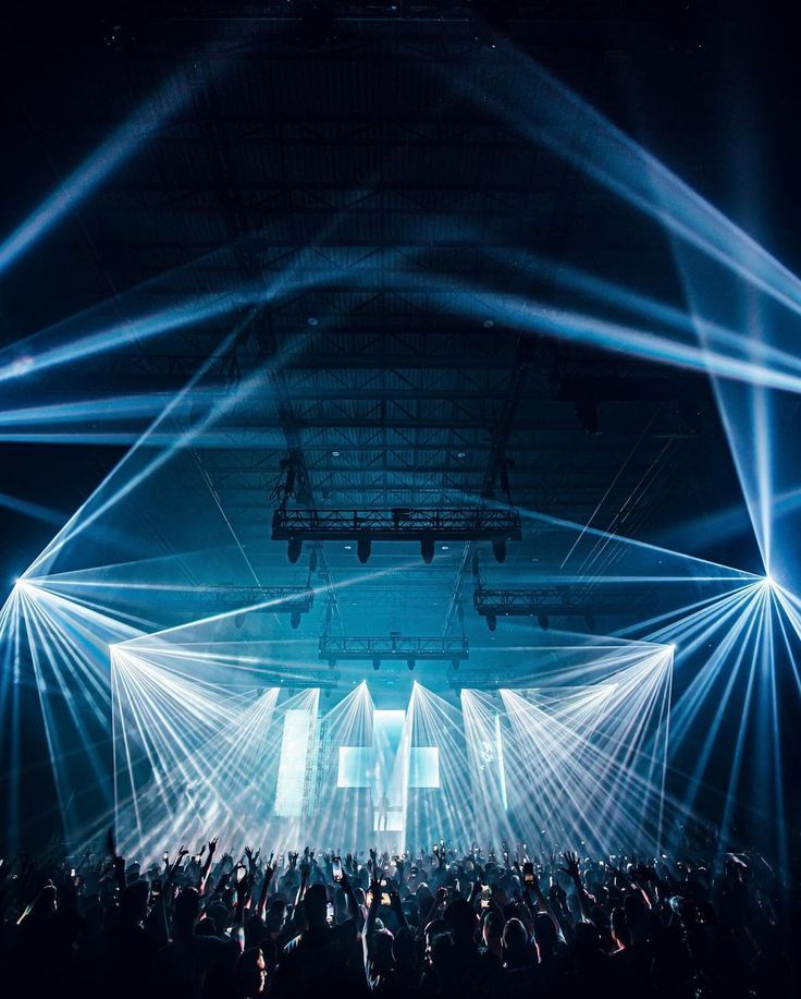 Stage framed by fanned light beams and screens